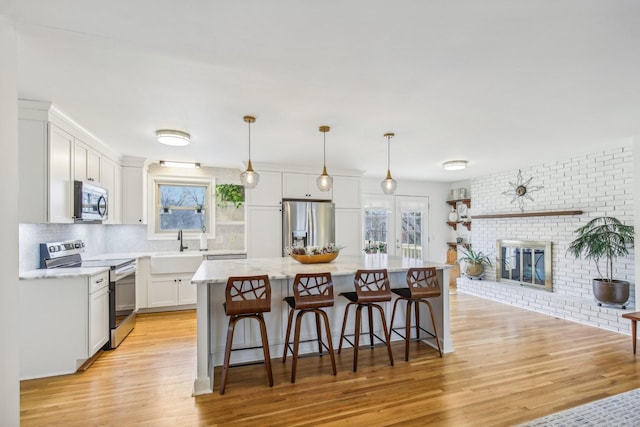 kitchen with white cabinets, appliances with stainless steel finishes, a kitchen island, and plenty of natural light