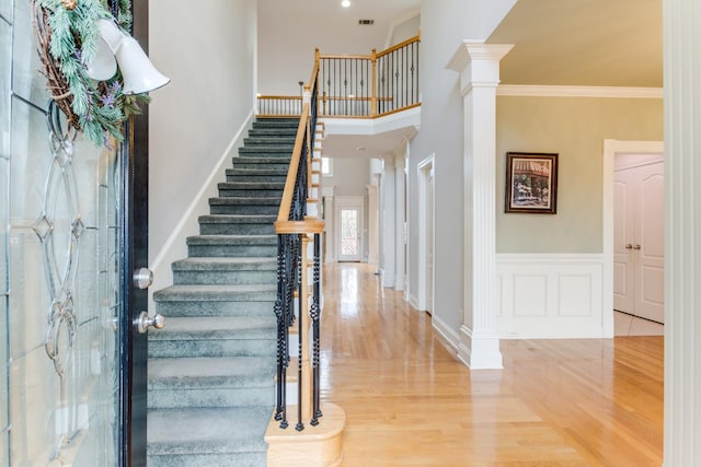 entryway with decorative columns, crown molding, and hardwood / wood-style flooring