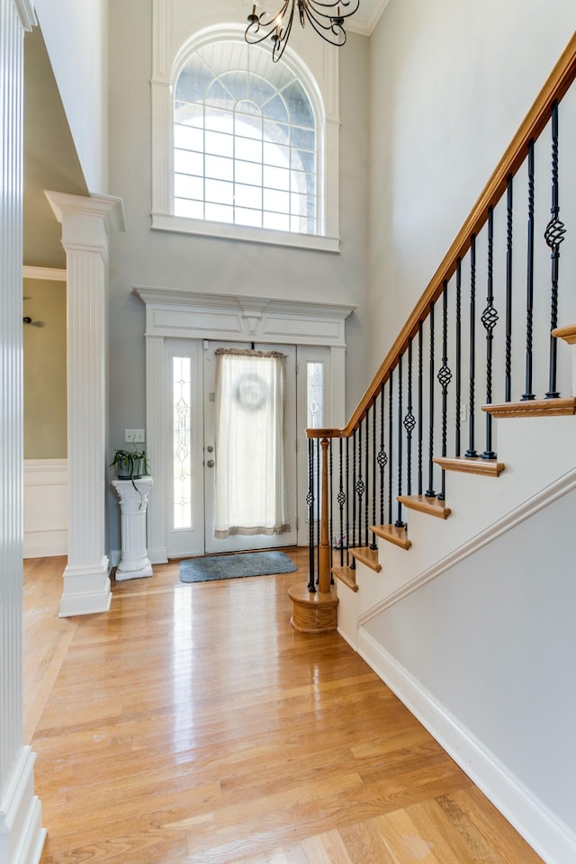 foyer with a chandelier, light wood-type flooring, crown molding, and a healthy amount of sunlight