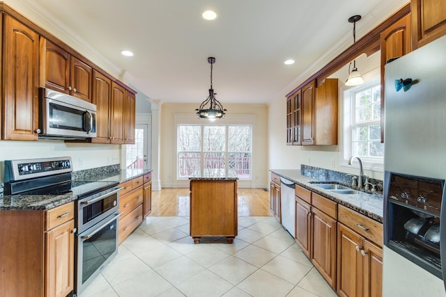 kitchen with appliances with stainless steel finishes, sink, dark stone countertops, a center island, and hanging light fixtures