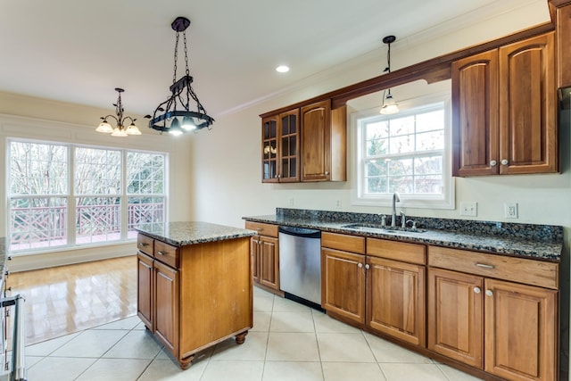 kitchen featuring dishwasher, sink, a healthy amount of sunlight, dark stone countertops, and decorative light fixtures