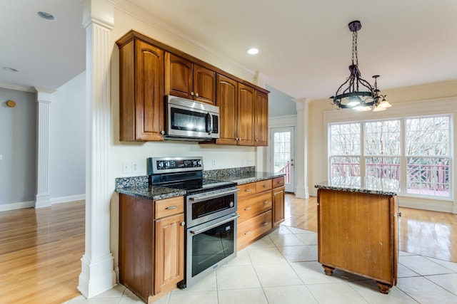 kitchen with appliances with stainless steel finishes, ornamental molding, pendant lighting, dark stone countertops, and a kitchen island