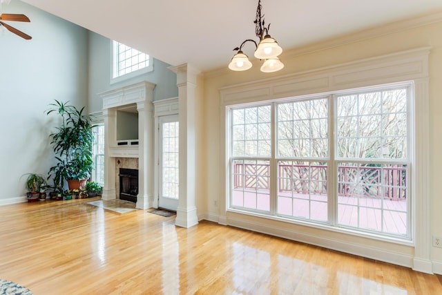 unfurnished living room featuring ceiling fan with notable chandelier, light hardwood / wood-style floors, and a tiled fireplace