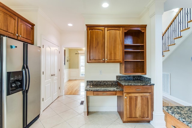 kitchen with stainless steel fridge, ornate columns, crown molding, dark stone countertops, and light tile patterned flooring