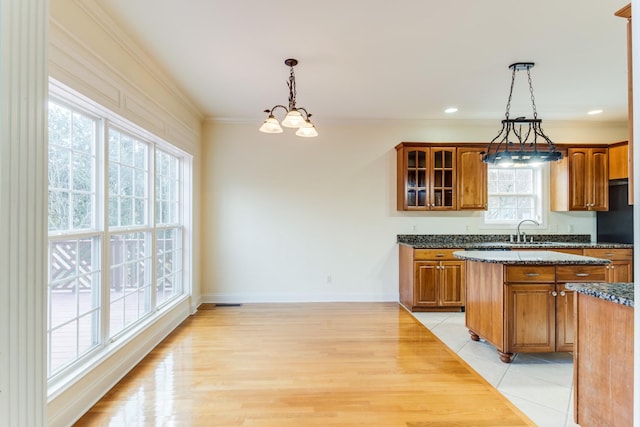 kitchen featuring sink, light tile patterned floors, decorative light fixtures, an inviting chandelier, and dark stone countertops