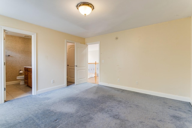 unfurnished bedroom featuring light carpet and ensuite bathroom