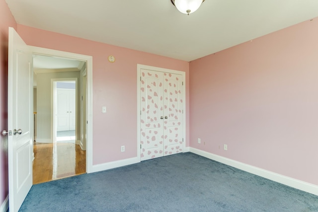 unfurnished bedroom with dark carpet, a closet, and crown molding