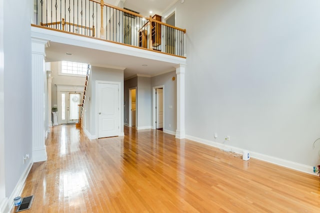 unfurnished room with ornamental molding, a high ceiling, and hardwood / wood-style flooring