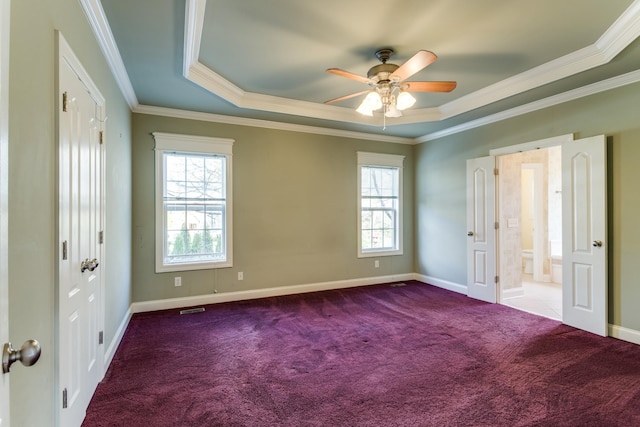 unfurnished bedroom with carpet, ceiling fan, ornamental molding, connected bathroom, and a tray ceiling