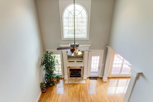 living room with ceiling fan, wood-type flooring, a fireplace, and a high ceiling