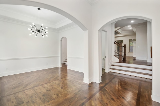 empty room with dark hardwood / wood-style floors, ornamental molding, and a notable chandelier