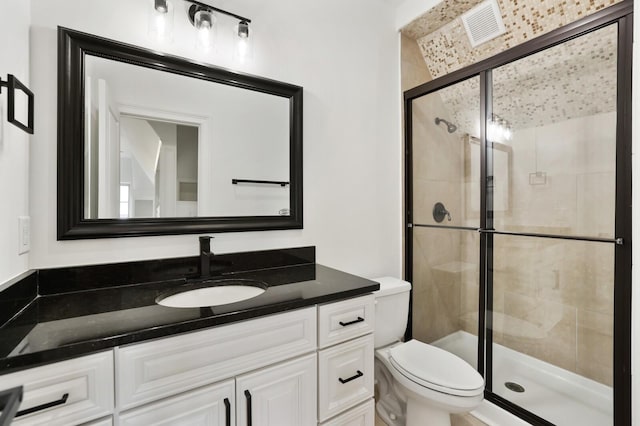 bathroom with vanity, a shower with shower door, and toilet