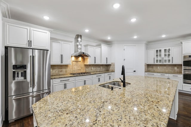 kitchen featuring appliances with stainless steel finishes, dark wood-type flooring, wall chimney range hood, sink, and white cabinets