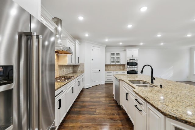 kitchen featuring appliances with stainless steel finishes, dark hardwood / wood-style flooring, wall chimney exhaust hood, sink, and white cabinetry