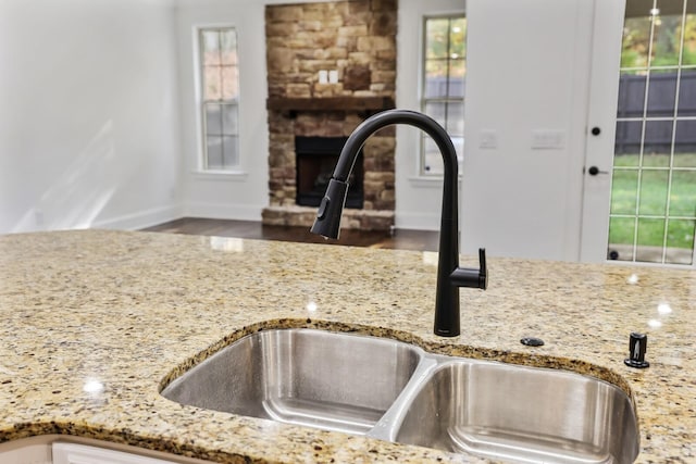 room details with light stone countertops, a stone fireplace, and sink