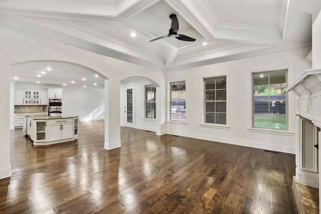 living room featuring ceiling fan, dark hardwood / wood-style flooring, beamed ceiling, and ornamental molding