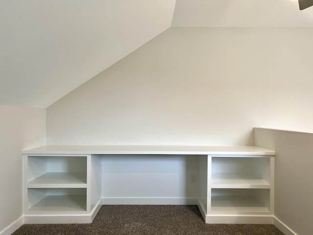 interior space featuring lofted ceiling and dark colored carpet