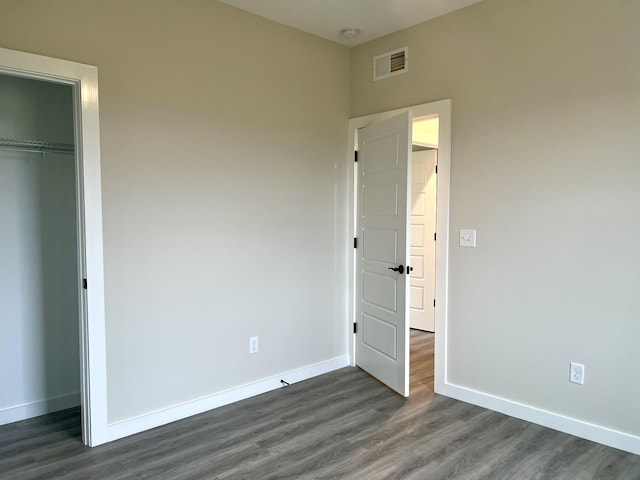 unfurnished bedroom featuring dark hardwood / wood-style flooring and a closet