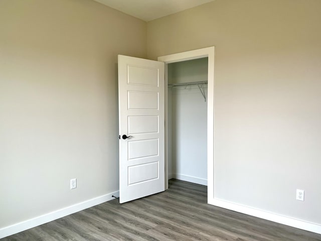 unfurnished bedroom with dark hardwood / wood-style flooring and a closet