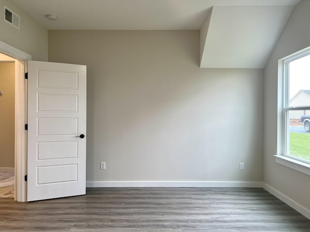 spare room with vaulted ceiling and hardwood / wood-style flooring