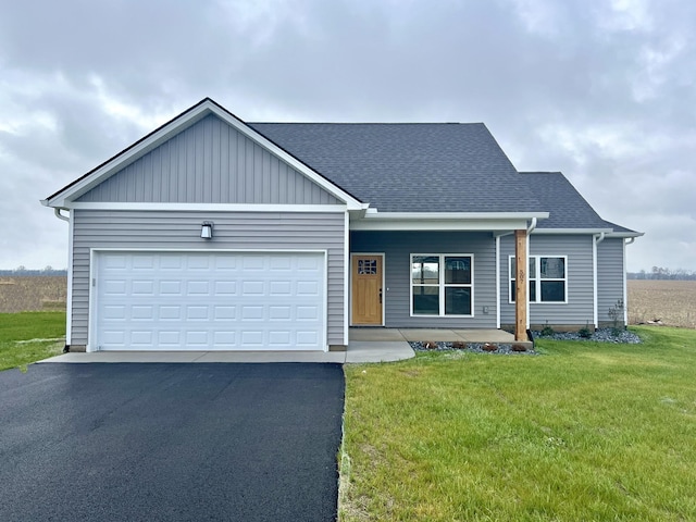 view of front of house featuring covered porch, a front yard, and a garage