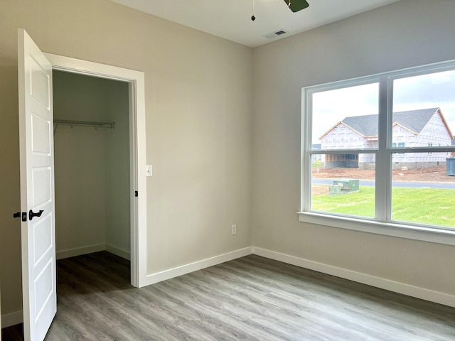 unfurnished bedroom with hardwood / wood-style flooring, ceiling fan, a spacious closet, and a closet