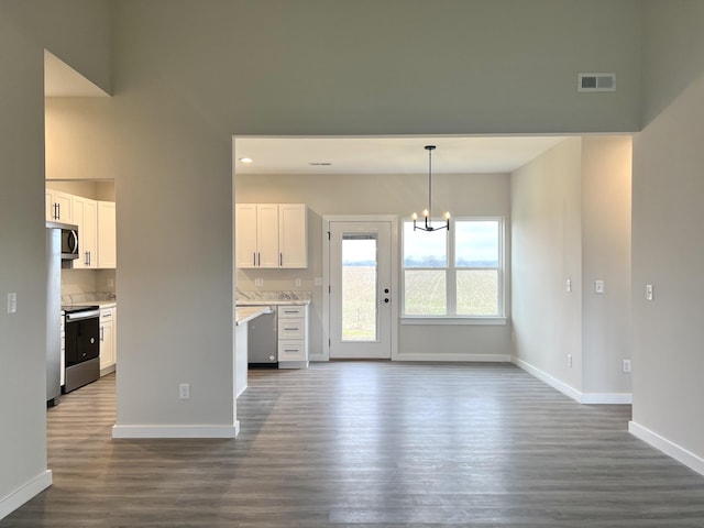 unfurnished living room with dark hardwood / wood-style flooring and an inviting chandelier