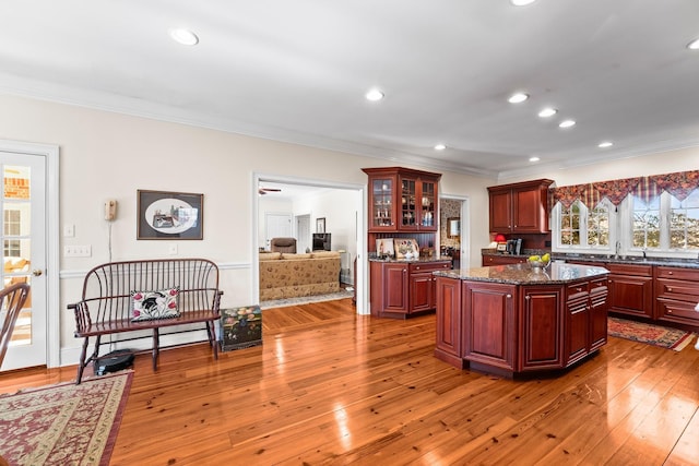 kitchen with a center island, sink, light wood-type flooring, and ornamental molding