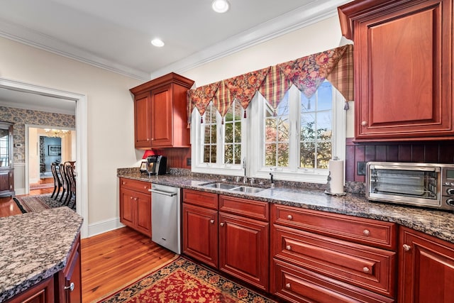 kitchen with sink, crown molding, dark stone counters, and light hardwood / wood-style flooring