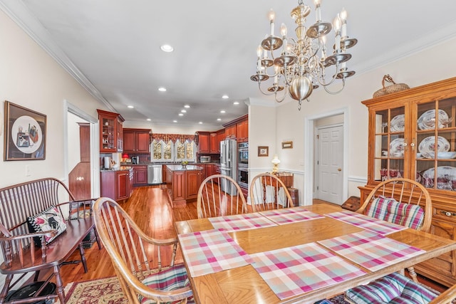 dining space featuring light wood-type flooring, crown molding, and a notable chandelier