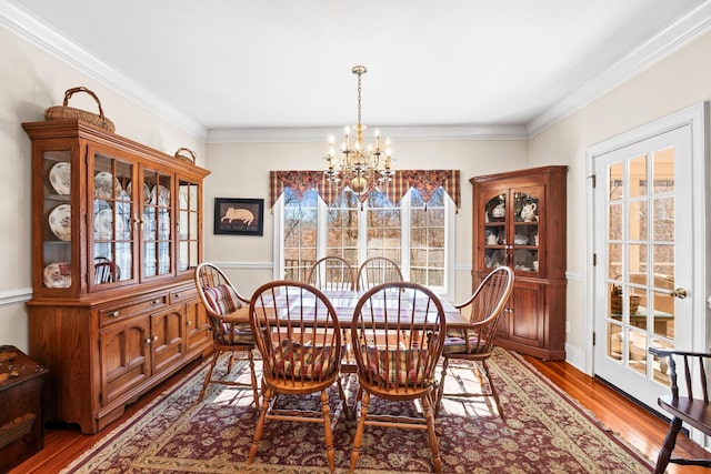 dining area featuring ornamental molding, plenty of natural light, wood-type flooring, and an inviting chandelier