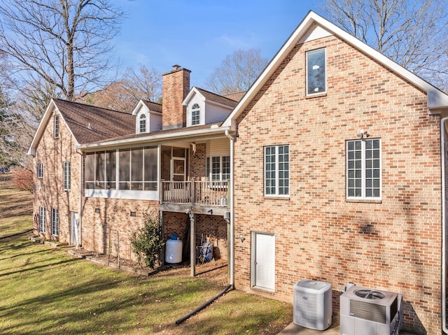 back of house featuring a lawn, a sunroom, and central AC unit