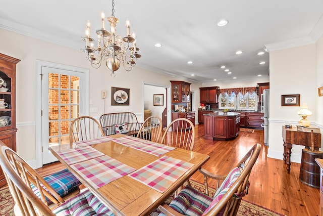 dining room featuring a notable chandelier, light wood-type flooring, and ornamental molding