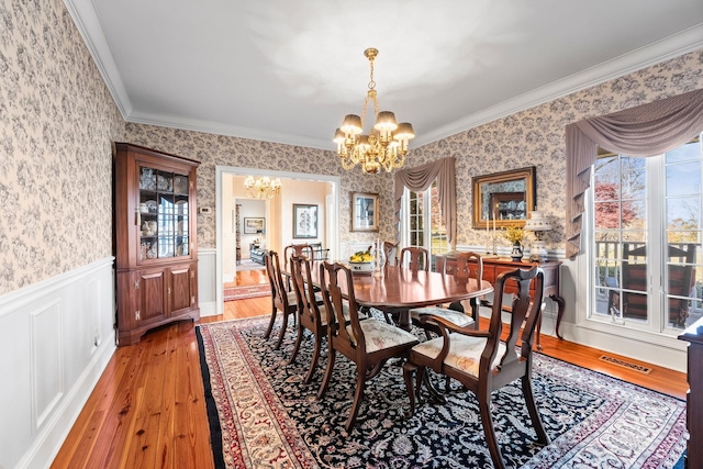 dining space featuring hardwood / wood-style flooring, an inviting chandelier, a wealth of natural light, and ornamental molding