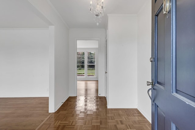 foyer with dark parquet flooring, crown molding, and a notable chandelier