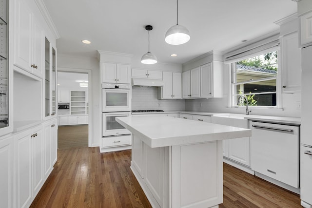 kitchen featuring dark hardwood / wood-style flooring, a center island, white cabinets, and white appliances