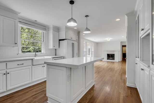 kitchen with a center island, sink, a brick fireplace, high end white fridge, and white cabinetry