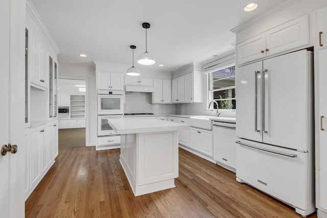 kitchen with white cabinetry, a center island, light hardwood / wood-style flooring, decorative light fixtures, and white appliances