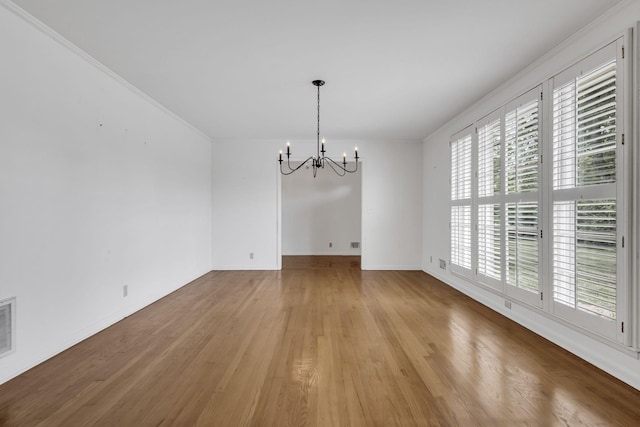 unfurnished dining area with a chandelier, crown molding, and light hardwood / wood-style flooring