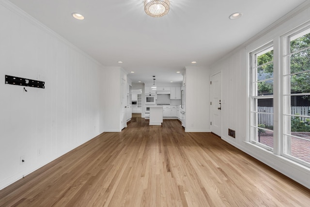 unfurnished living room featuring a chandelier, light hardwood / wood-style floors, and ornamental molding