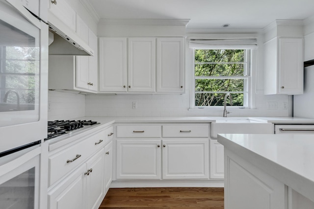 kitchen featuring white oven, white cabinetry, stainless steel gas cooktop, and tasteful backsplash