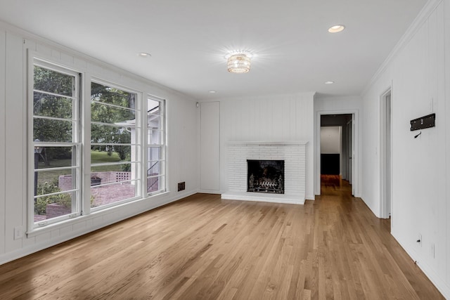 unfurnished living room featuring a fireplace, light hardwood / wood-style floors, and crown molding