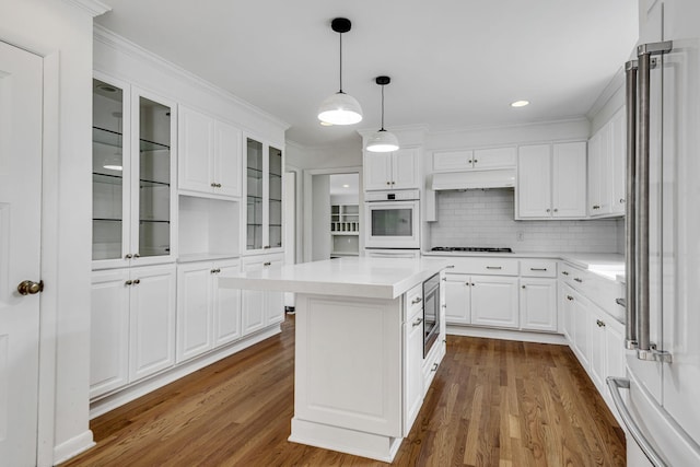 kitchen featuring custom exhaust hood, white cabinetry, appliances with stainless steel finishes, a kitchen island, and wood-type flooring