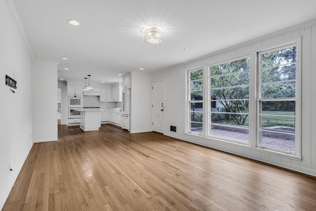 unfurnished living room with light wood-type flooring and ornamental molding