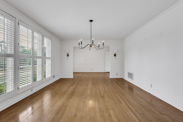 unfurnished dining area featuring ornamental molding, a notable chandelier, and light wood-type flooring