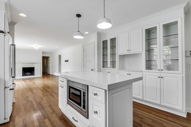 kitchen featuring dark wood-type flooring, a center island, white fridge, white cabinetry, and stainless steel microwave