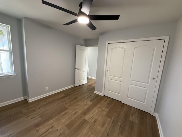 unfurnished bedroom with ceiling fan, a closet, and dark wood-type flooring