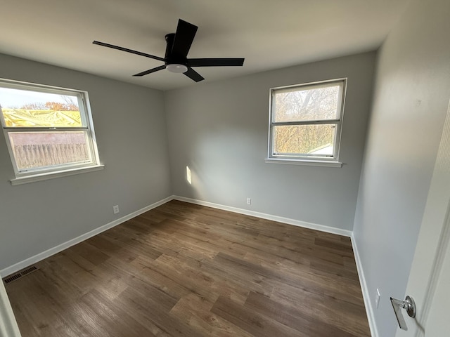 unfurnished room featuring a wealth of natural light, dark hardwood / wood-style flooring, and ceiling fan