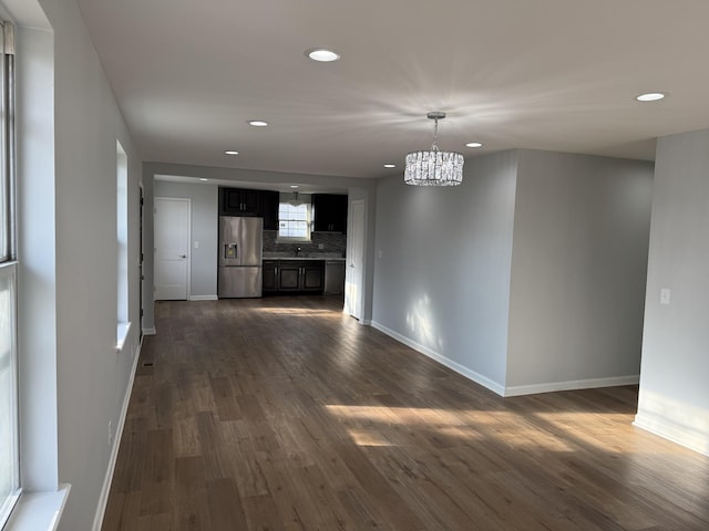 unfurnished living room featuring dark wood-type flooring and an inviting chandelier