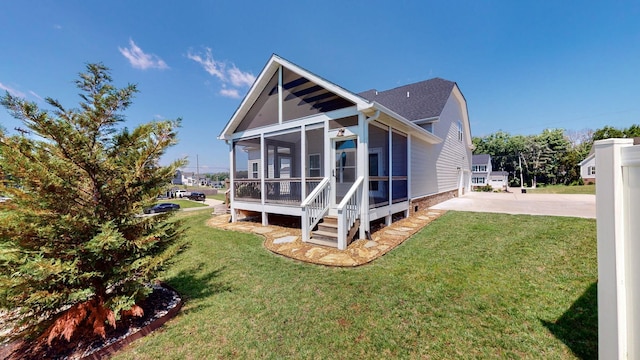 back of property featuring a lawn, a patio area, and a sunroom